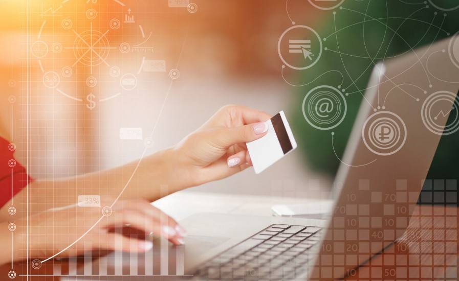 A person holding a credit card while using a laptop