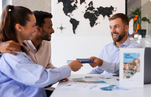Travel consultant handing documents to a couple while planning an international trip in an office