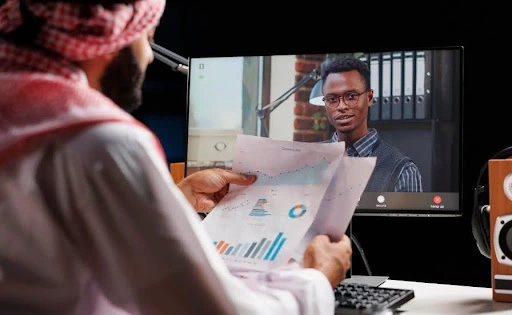 Professional reviewing financial reports during an online video consultation with a business advisor on a computer screen