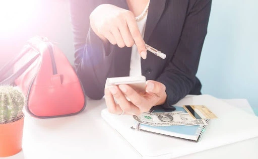 Tracking expenses on mobile phone with cash and notebook – personal budgeting and savings management concept