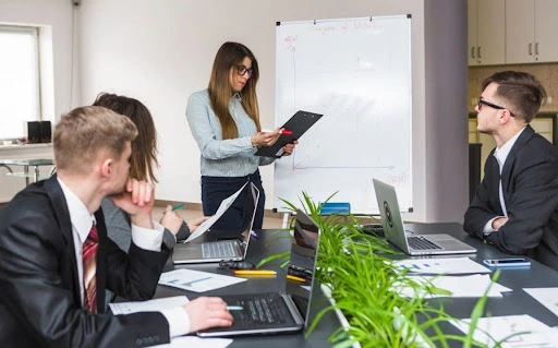 Corporate team in a meeting room reviewing reports while a manager presents business strategy on a whiteboard during a planning session on setting up a business in meydan free zone