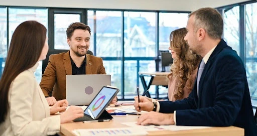 A smiling professional consultant leads a meeting with a group of international entrepreneurs