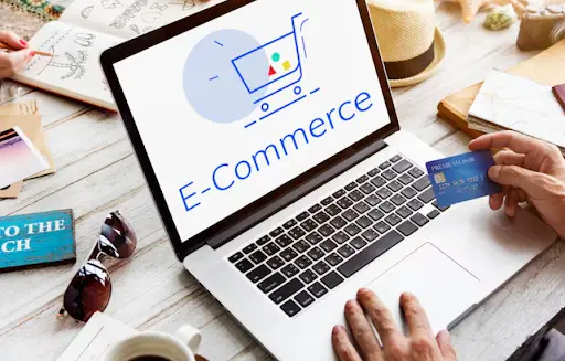 An e-commerce graphic with a shopping cart icon, with a hand holding a credit card nearby.
