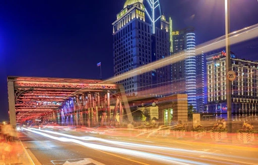 A scenic view of an urban bridge at night with motion-blurred car lights, reflecting the "dynamic business environment" and "high-end infrastructure" of world-class financial centers