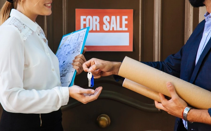 man handing over the keys of a house sold to a woman
