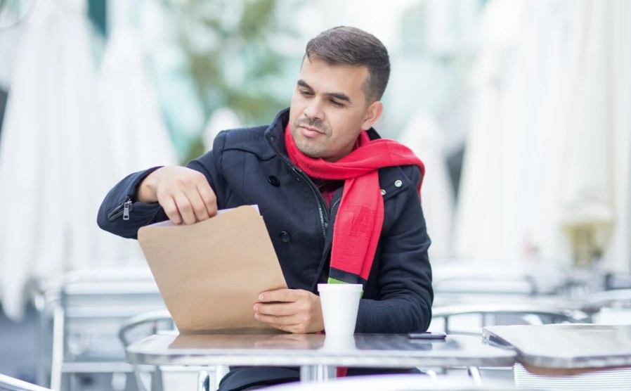 young businessman opening letter at cafe