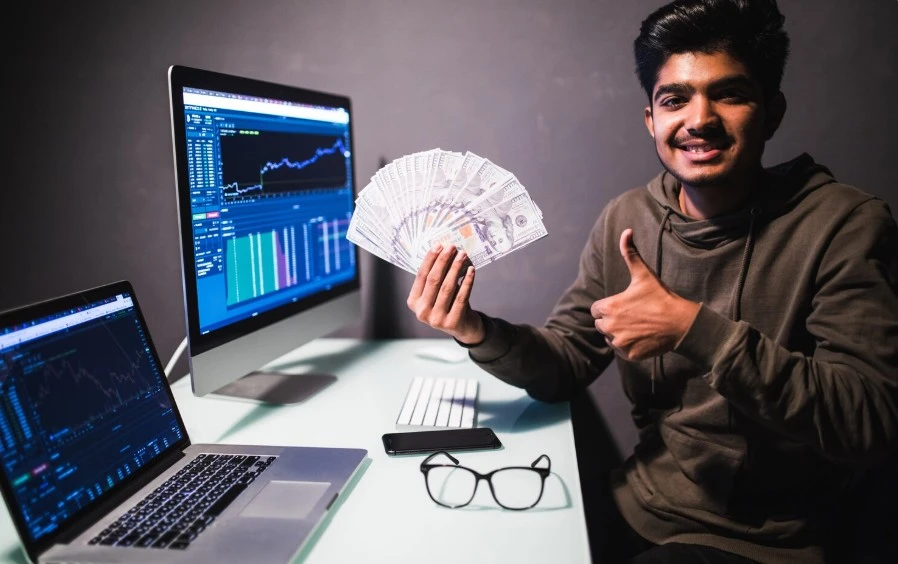 a crypto millionaire with two screens opened and trading graph being displayed on them