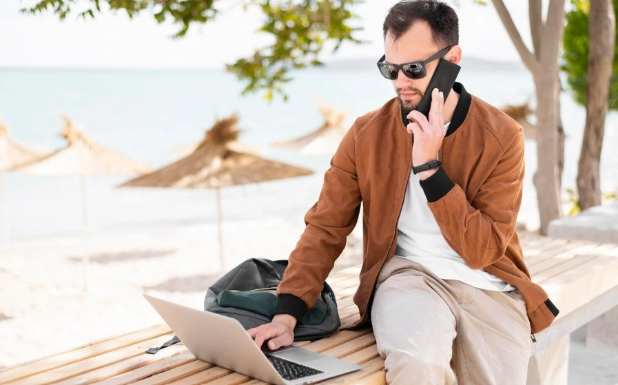 Front view of man working on laptop at the beach